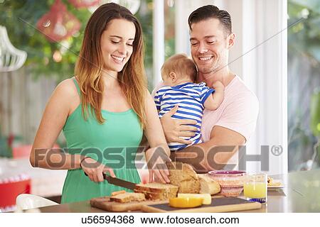 Stock Photo - Mother Making Snack For Family In Kitchen. Fotosearch