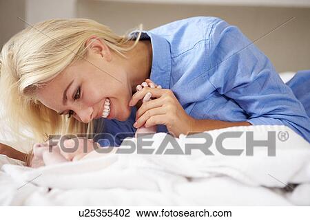 Mother Playing With Baby Girl As They Lie In Bed Together View Large Photo Image Stock Image - Mother Playing With Baby Girl As They Lie In Bed Together. Fotosearch