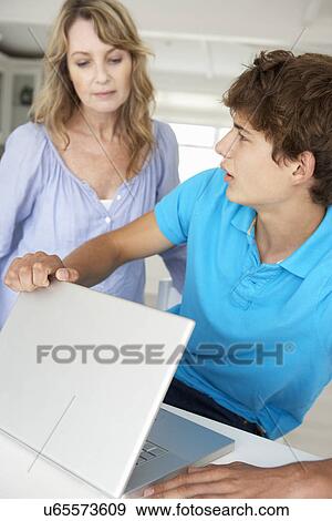 Mother supervising teenage son using laptop View Large Photo Image Stock Photo - Mother supervising teenage son using laptop. Fotosearch