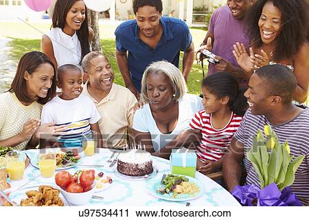 Stock Image - Multi Generation Family Celebrating Birthday In Garden. Fotosearch