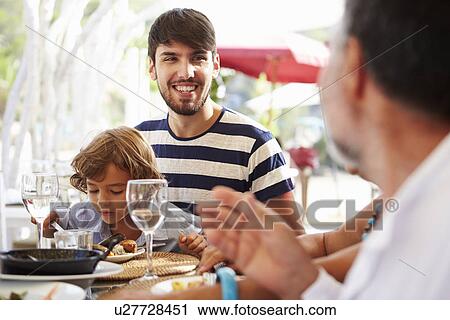 Stock Image - Multi Generation Family Enjoying Meal In Restaurant. Fotosearch