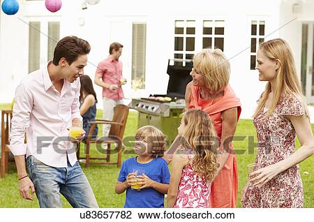 Stock Image - Multi Generation Family Enjoying Meal In Garden Together. Fotosearch