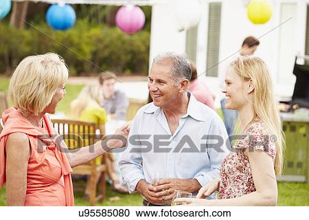 Stock Image - Multi Generation Family Enjoying Meal In Garden Together. Fotosearch