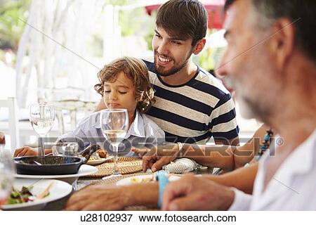 Stock Photo - Multi Generation Family Enjoying Meal In Restaurant. Fotosearch