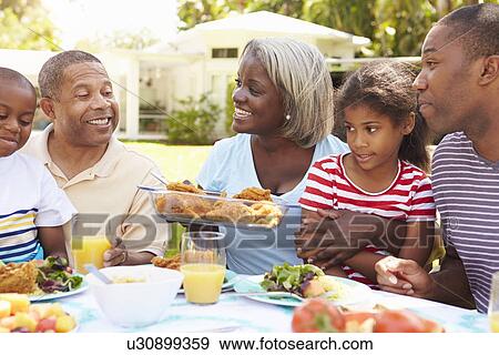 Multi Generation Family Enjoying Meal In Garden Together View Large Photo Image Stock Photo - Multi Generation Family Enjoying Meal In Garden Together. Fotosearch