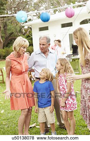 Stock Photo - Multi Generation Family Enjoying Meal In Garden Together. Fotosearch