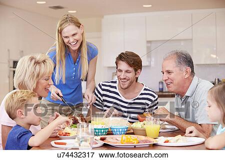 Stock Photo - Multi Generation Family Enjoying Meal At Home Together. Fotosearch