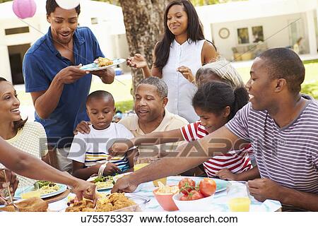 Multi Generation Family Enjoying Meal In Garden Together View Large Photo Image Stock Photo - Multi Generation Family Enjoying Meal In Garden Together. Fotosearch