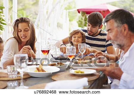 Stock Photo - Multi Generation Family Enjoying Meal In Restaurant. Fotosearch
