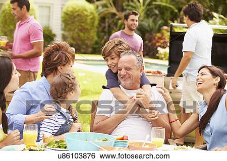 Stock Photograph - Multi Generation Family Enjoying Meal In Garden Together. Fotosearch