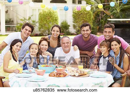 Stock Photography - Multi Generation Family Enjoying Meal In Garden Together. Fotosearch