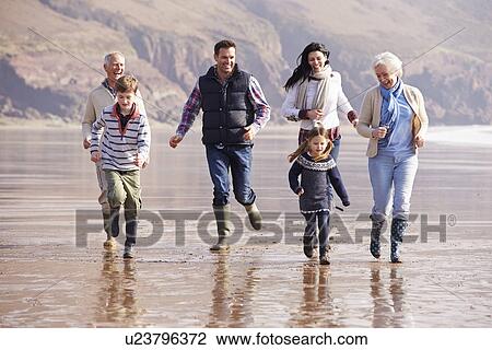 Stock Image - Multi Generation Family Running On Winter Beach. Fotosearch