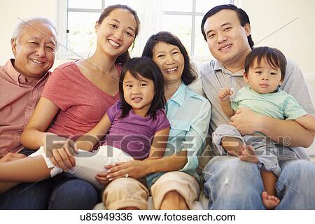 Stock Photograph - Multi Generation Family Sitting On Sofa At Home Together. Fotosearch