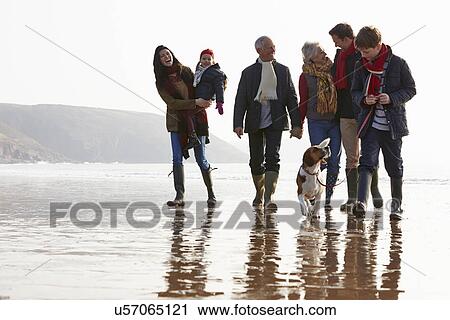 Stock Image - Multi Generation Family Walking On Winter Beach With Dog. Fotosearch
