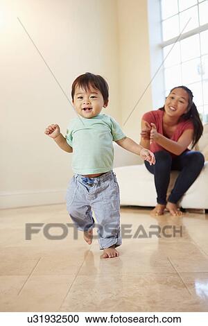 Stock Image - One Year Old Boy Taking First Steps With Mother. Fotosearch