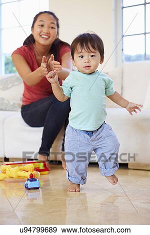 Stock Photo - One Year Old Boy Taking First Steps With Mother. Fotosearch