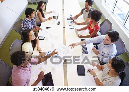 Stock Photo - Overhead View Of Designers Meeting To Discuss New Ideas. Fotosearch