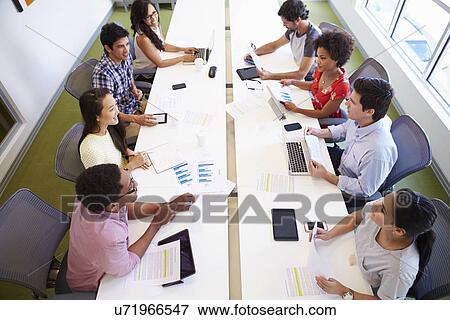 Stock Photo - Overhead View Of Designers Meeting To Discuss New Ideas. Fotosearch