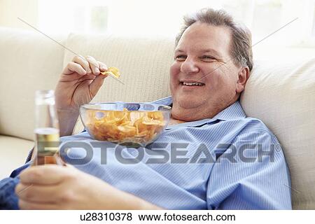 Overweight Man At Home Eating Chips And Drinking Beer View Large Photo Image Stock Photo - Overweight Man At Home Eating Chips And Drinking Beer. Fotosearch