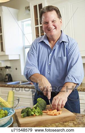 Stock Photo - Overweight Man Preparing Vegetables in Kitchen. Fotosearch