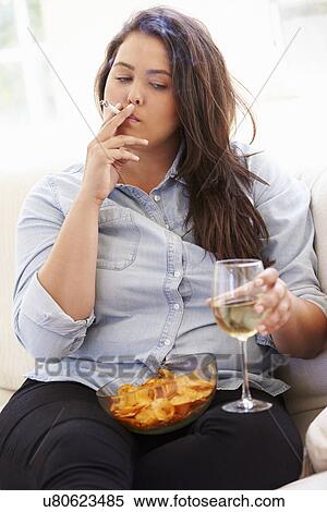 Stock Photography - Overweight Woman Eating Chips, Drinking Wine And Smoking. Fotosearch