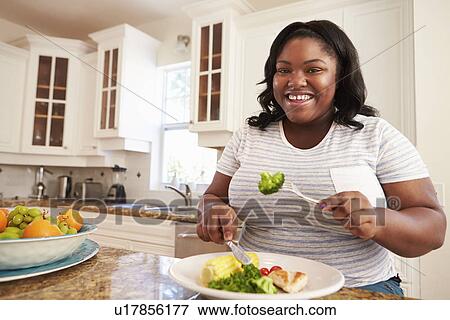 Overweight Woman Eating Healthy Meal in Kitchen View Large Photo Image Stock Photo - Overweight Woman Eating Healthy Meal in Kitchen. Fotosearch