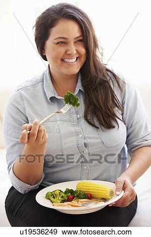 Overweight Woman Eating Healthy Meal Sitting On Sofa View Large Photo Image Stock Photo - Overweight Woman Eating Healthy Meal Sitting On Sofa. Fotosearch