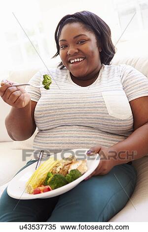 Overweight Woman Eating Healthy Meal Sitting On Sofa View Large Photo Image Stock Photography - Overweight Woman Eating Healthy Meal Sitting On Sofa. Fotosearch
