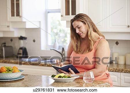 Stock Image - Overweight Woman On Diet Keeping Food Journal. Fotosearch
