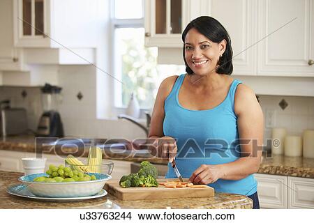 Picture - Overweight Woman Preparing Vegetables In Kitchen. Fotosearch