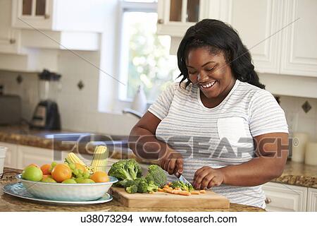 Picture - Overweight Woman Preparing Vegetables in Kitchen. Fotosearch