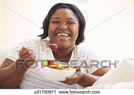 Overweight Woman Sitting On Sofa Eating Bowl Of Fresh Fruit View Large Photo Image Stock Image - Overweight Woman Sitting On Sofa Eating Bowl Of Fresh Fruit. Fotosearch