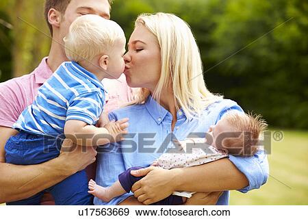 Stock Photo - Parents Holding Young Children In Garden. Fotosearch