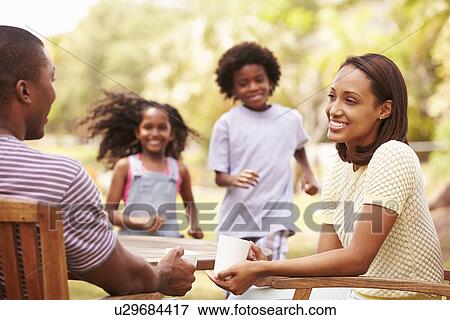 Parents Relaxing Whilst Children Play In Garden View Large Photo Image Stock Photo - Parents Relaxing Whilst Children Play In Garden . Fotosearch