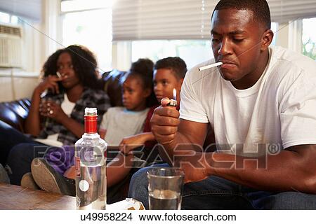 Picture - Parents Sit On Sofa With Children Smoking And Drinking. Fotosearch