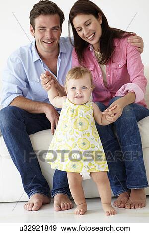 Stock Photo - Parents teaching baby girl to walk. Fotosearch