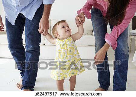 Parents teaching baby girl to walk View Large Photo Image Stock Photo - Parents teaching baby girl to walk. Fotosearch