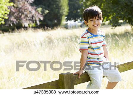Portrait Of Asian Boy Sitting On Fence In Countryside View Large Photo Image Stock Photo - Portrait Of Asian Boy Sitting On Fence In Countryside. Fotosearch