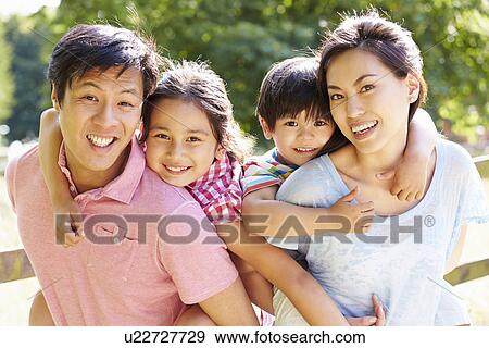 Stock Photo - Portrait Of Asian Family Enjoying Walk In Summer Countryside. Fotosearch