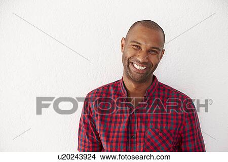 Picture - Portrait Of Casually Dressed Man Leaning Against White Wall. Fotosearch