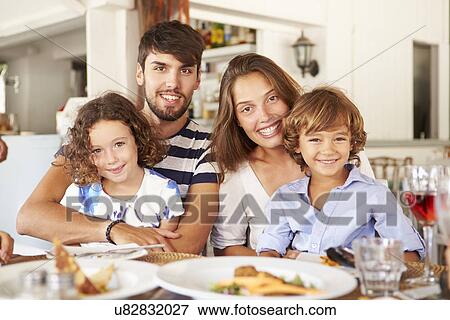 Stock Photo - Portrait Of Family Enjoying Meal In Restaurant. Fotosearch