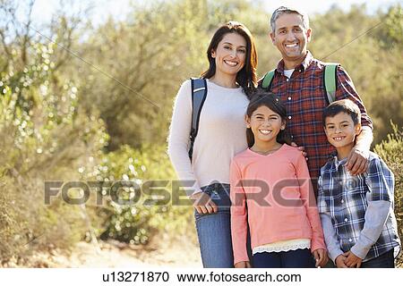 Stock Image - Portrait Of Family Hiking In Countryside Wearing Backpacks. Fotosearch