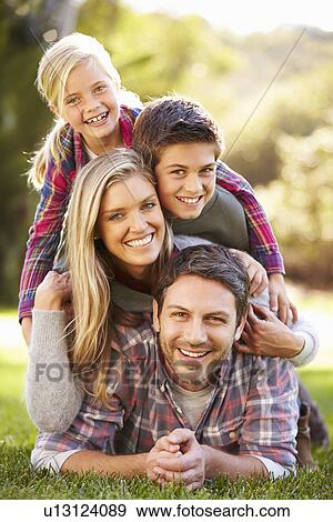 Stock Photo - Portrait Of Family Lying On Grass In Countryside. Fotosearch