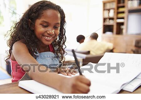 Stock Image - Portrait Of Girl Doing Homework At Table. Fotosearch