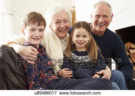 Stock Photo - Portrait Of Grandparents Sitting On Sofa With Grandchildren. Fotosearch