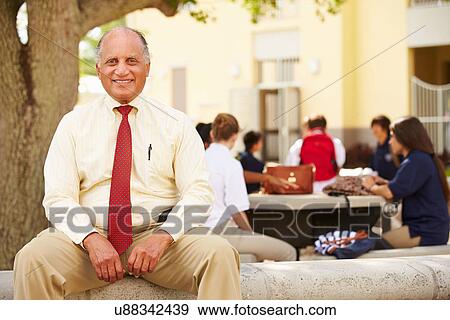 Stock Photo - Portrait Of High School Teacher Sitting On School Campus. Fotosearch