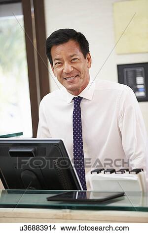 Picture - Portrait Of Male Receptionist At Hotel Front Desk. Fotosearch
