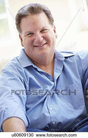 Stock Image - Portrait Of Overweight Man Sitting On Sofa. Fotosearch