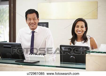 Stock Photography - Portrait Of Reception Staff At Hotel Front Desk. Fotosearch