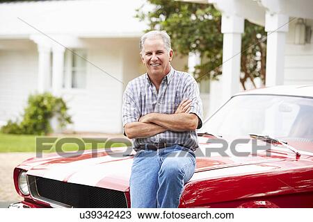 Stock Image - Portrait Of Retired Senior Man With Restored Car. Fotosearch